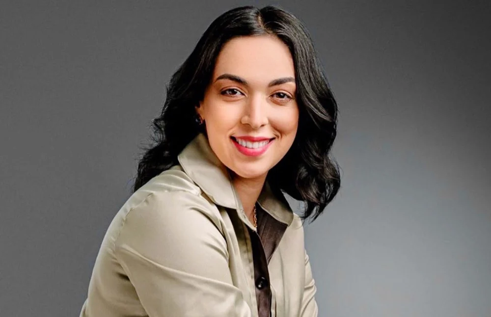 Retrato sorridente de Sara Medeiros, com camisa clara.